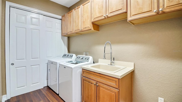 clothes washing area featuring cabinets, dark hardwood / wood-style floors, washing machine and dryer, and sink