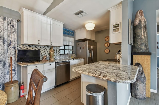 kitchen with a kitchen bar, light stone counters, white cabinetry, and stainless steel appliances