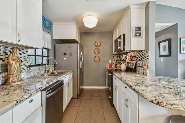 kitchen featuring light stone countertops, appliances with stainless steel finishes, tasteful backsplash, sink, and white cabinetry