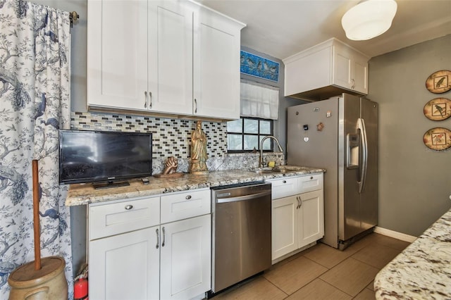 kitchen featuring light stone countertops, tasteful backsplash, stainless steel appliances, sink, and white cabinetry