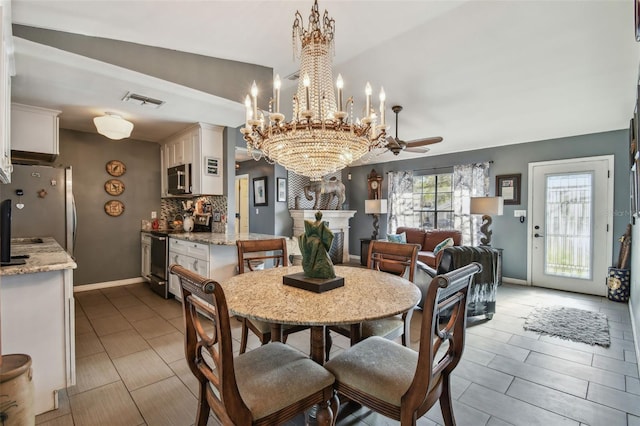 dining room with ceiling fan with notable chandelier, a large fireplace, and lofted ceiling