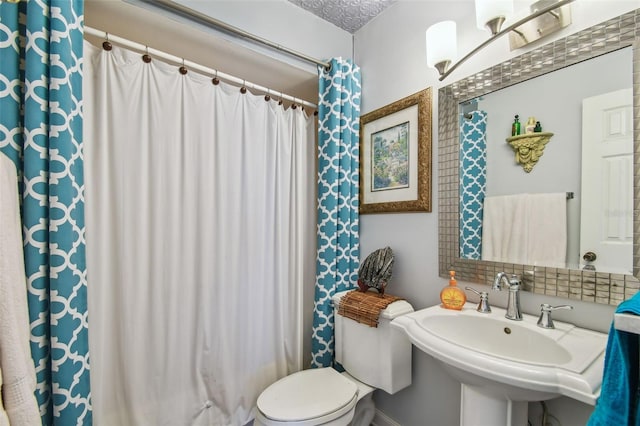 bathroom with a textured ceiling, toilet, and sink