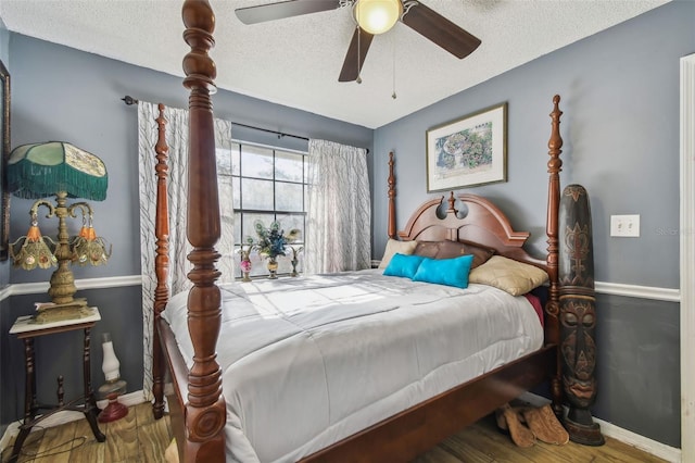 bedroom with hardwood / wood-style flooring, ceiling fan, and a textured ceiling