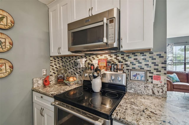 kitchen featuring light stone counters, appliances with stainless steel finishes, white cabinets, and decorative backsplash