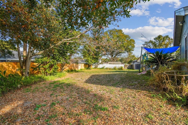 view of yard with a storage shed, a fenced backyard, and an outbuilding