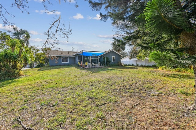 rear view of house with a lawn and fence