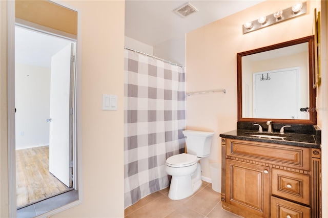 bathroom with toilet, vanity, and tile patterned floors