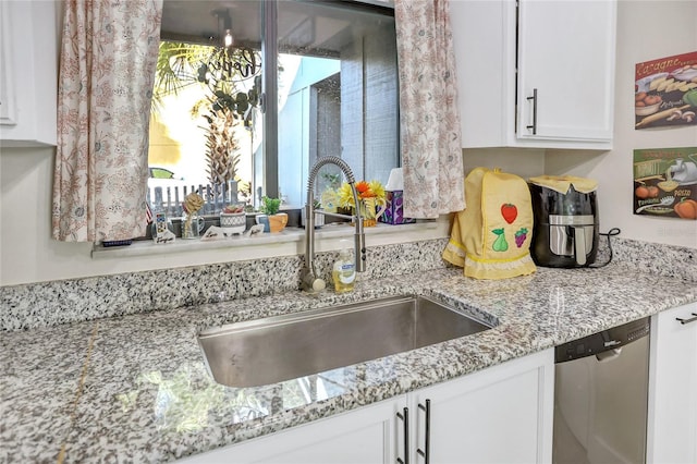 kitchen with stainless steel dishwasher, light stone counters, white cabinetry, and sink