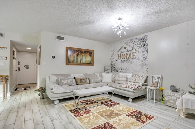 living room with a chandelier, light hardwood / wood-style floors, and a textured ceiling