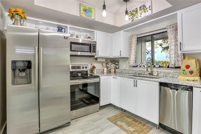 kitchen with sink, light hardwood / wood-style flooring, light stone countertops, white cabinetry, and stainless steel appliances