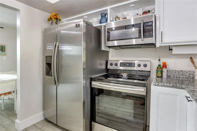 kitchen featuring light stone countertops, appliances with stainless steel finishes, light hardwood / wood-style flooring, and white cabinetry