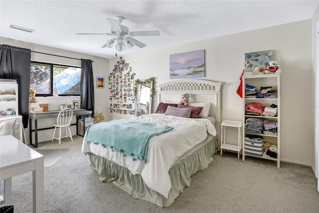 carpeted bedroom featuring ceiling fan and a textured ceiling