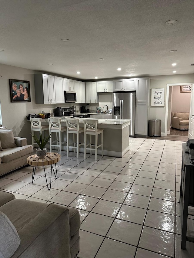 living room featuring sink, light tile patterned flooring, and a textured ceiling