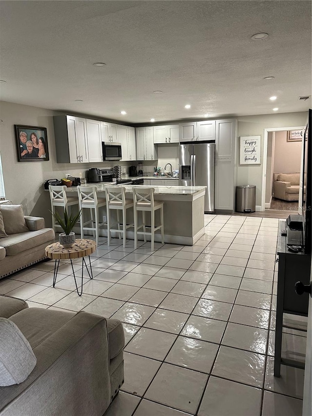 living room with light tile patterned floors, a textured ceiling, and sink