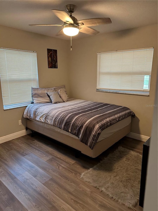 bedroom featuring ceiling fan, wood-type flooring, and multiple windows