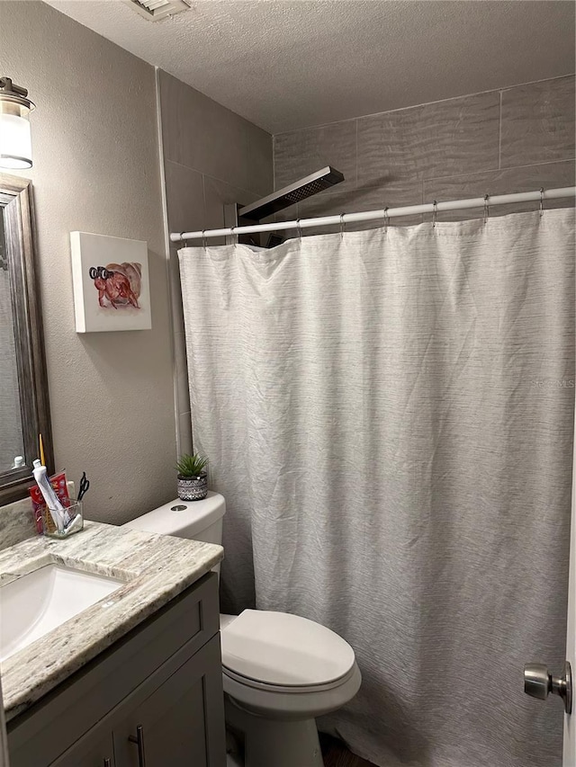 bathroom featuring vanity, toilet, a textured ceiling, and walk in shower