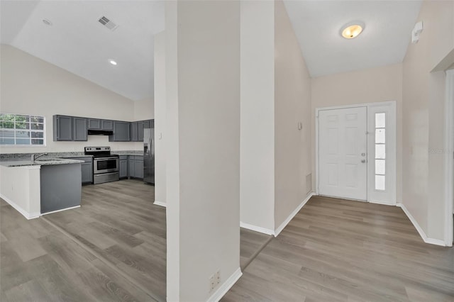 entryway with light wood-type flooring, high vaulted ceiling, and sink