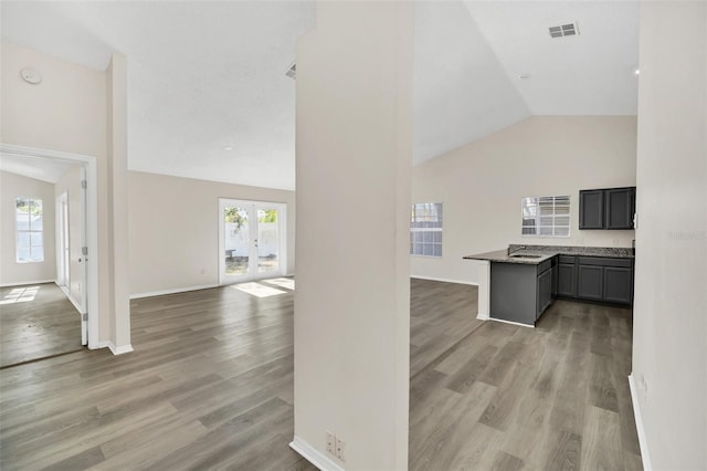 interior space featuring kitchen peninsula, sink, lofted ceiling, and light wood-type flooring