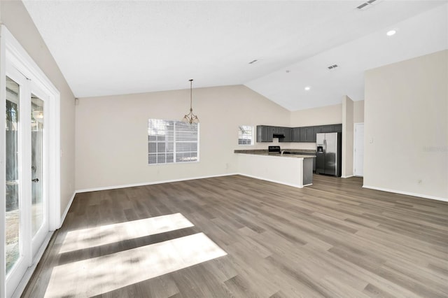 unfurnished living room featuring hardwood / wood-style floors, vaulted ceiling, and a healthy amount of sunlight