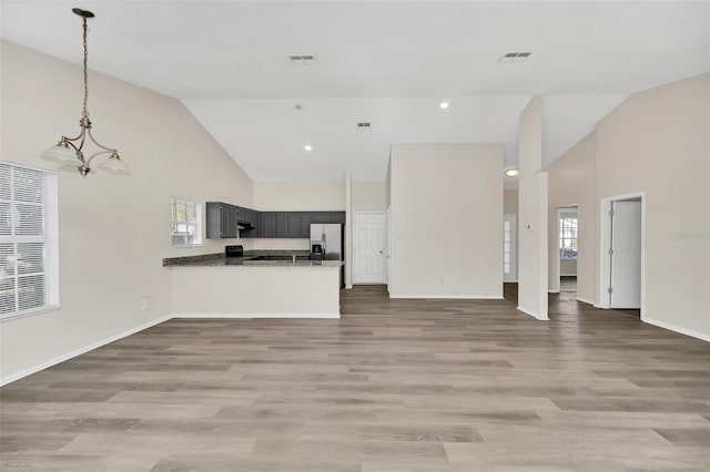 unfurnished living room featuring wood-type flooring, high vaulted ceiling, and a chandelier