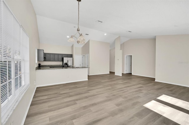 unfurnished living room with wood-type flooring, high vaulted ceiling, and an inviting chandelier