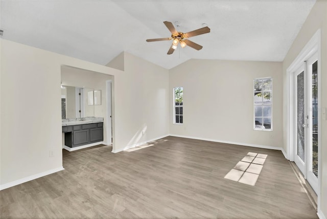 unfurnished living room featuring hardwood / wood-style floors, plenty of natural light, ceiling fan, and lofted ceiling