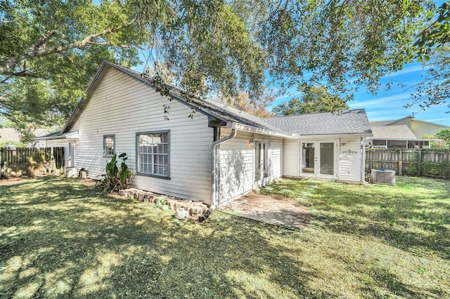 rear view of house featuring central AC unit, a yard, and french doors