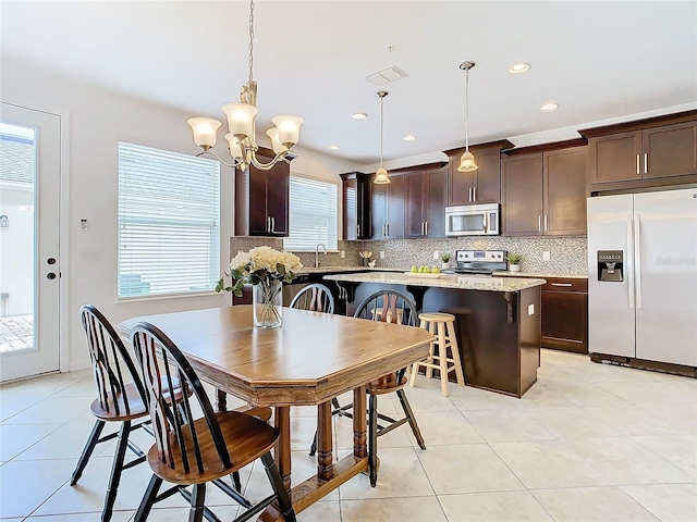 dining area featuring sink, light tile patterned floors, and an inviting chandelier