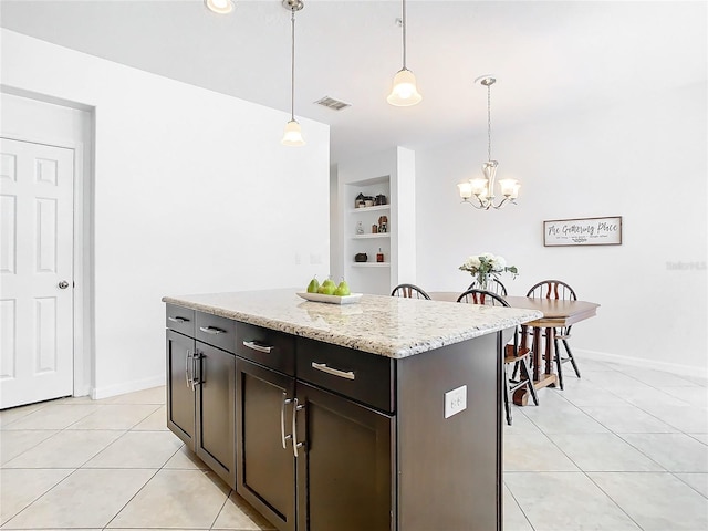 kitchen with light tile patterned flooring, a kitchen island, pendant lighting, built in features, and dark brown cabinets