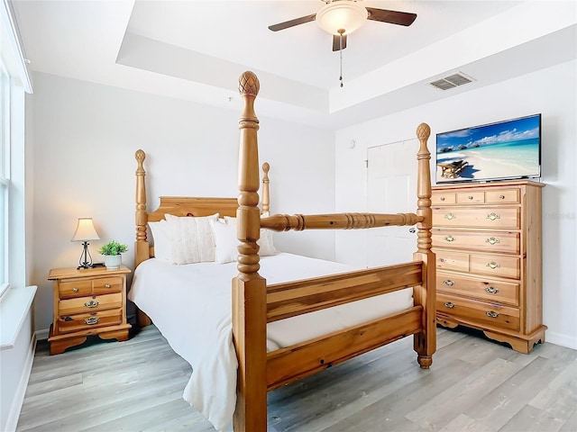 bedroom featuring a tray ceiling, light hardwood / wood-style floors, and ceiling fan