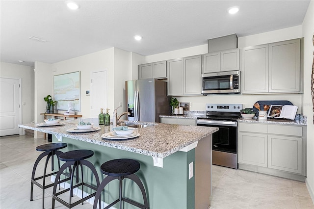 kitchen featuring a center island with sink, sink, a breakfast bar area, and appliances with stainless steel finishes