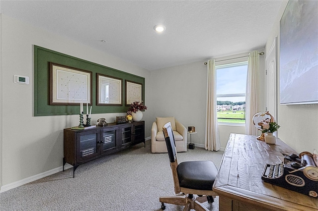 carpeted home office featuring a textured ceiling