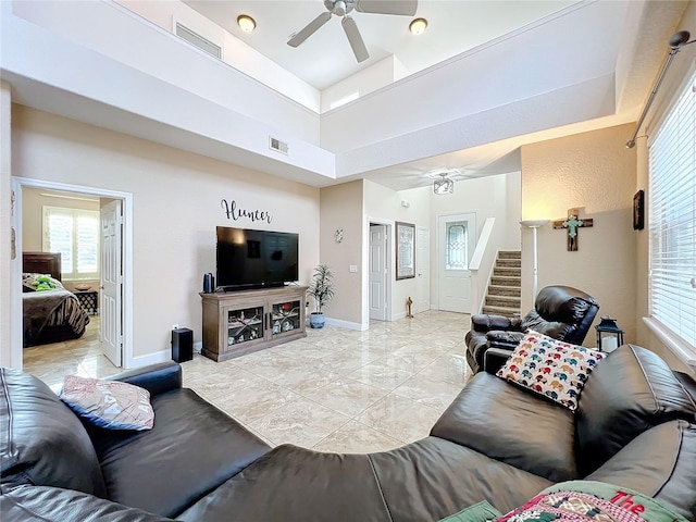 living room with ceiling fan and a high ceiling