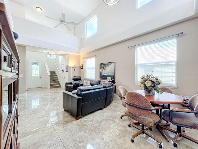 living room with ceiling fan, a high ceiling, and a wealth of natural light