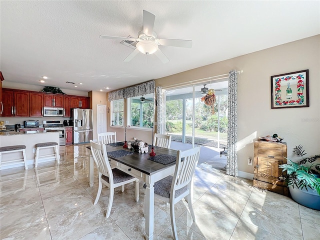 dining area featuring ceiling fan and a textured ceiling