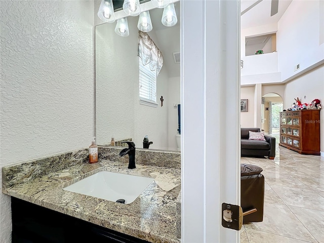 bathroom featuring a towering ceiling, vanity, and a healthy amount of sunlight