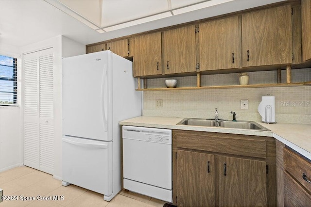 kitchen featuring backsplash, sink, light tile patterned floors, and white appliances