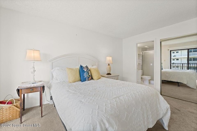 bedroom with a textured ceiling, light carpet, and connected bathroom