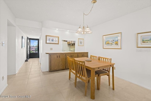 tiled dining space with a chandelier and a textured ceiling