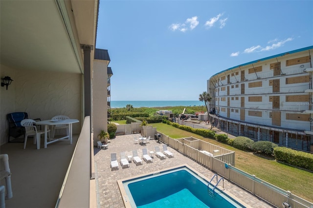 community pool with a water view, a patio area, and a fenced backyard