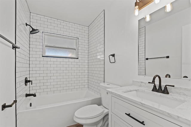 full bathroom featuring vanity, tiled shower / bath combo, and toilet