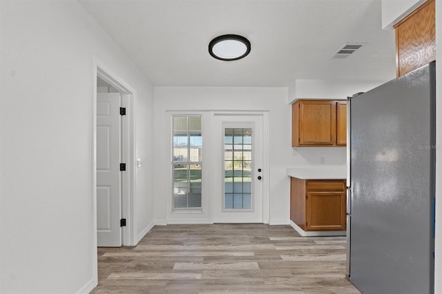 kitchen with light wood-type flooring and stainless steel refrigerator