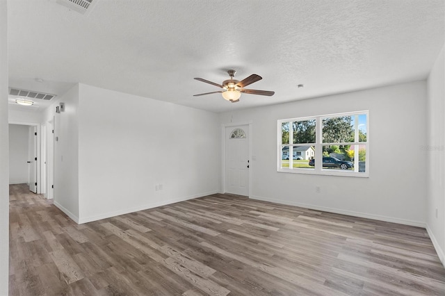 empty room featuring a textured ceiling, light wood-type flooring, and ceiling fan