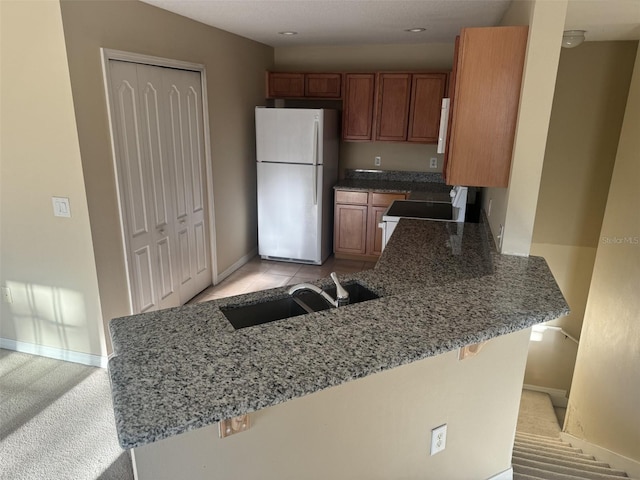 kitchen featuring a kitchen breakfast bar, kitchen peninsula, light carpet, and white appliances