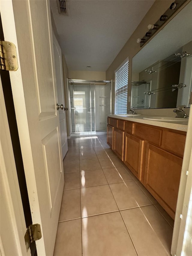 bathroom featuring tile patterned flooring, vanity, and a shower with shower door