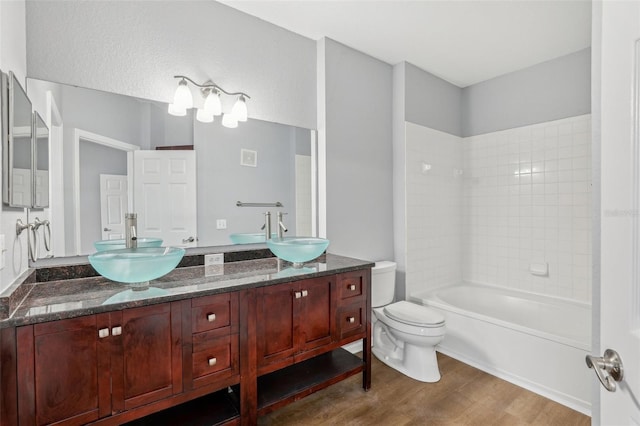 full bathroom featuring hardwood / wood-style floors, vanity, toilet, and tiled shower / bath combo