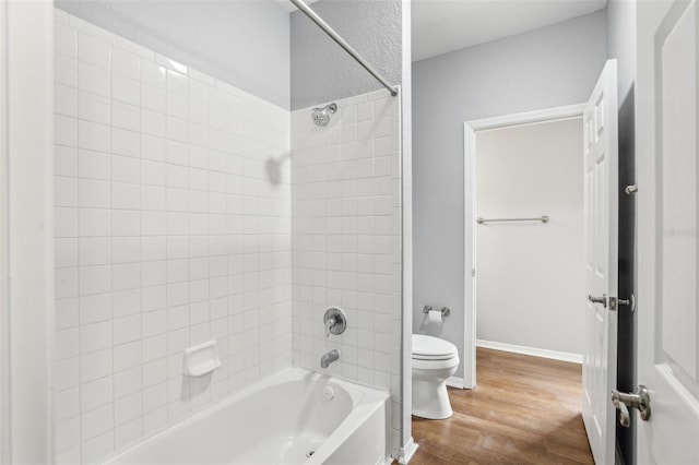 bathroom with toilet, hardwood / wood-style floors, and tiled shower / bath