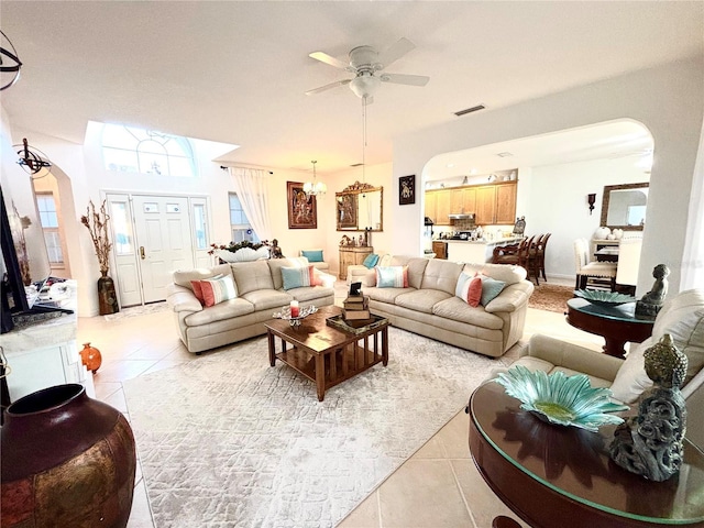 tiled living room featuring ceiling fan with notable chandelier