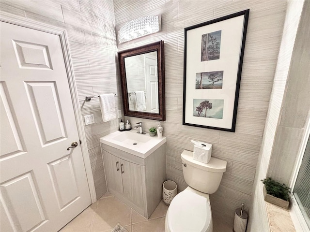 bathroom with tile patterned flooring, vanity, toilet, and tile walls