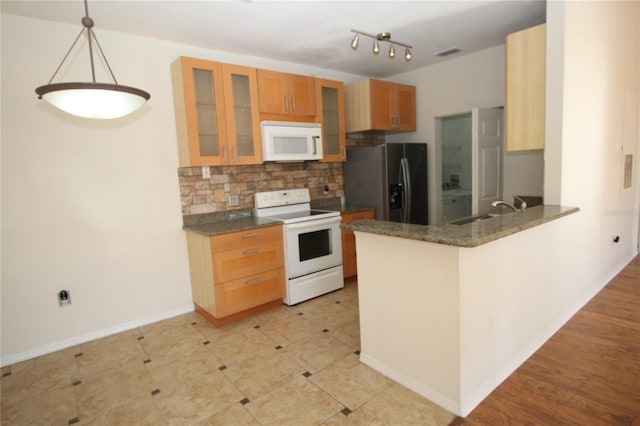 kitchen with pendant lighting, white appliances, backsplash, sink, and kitchen peninsula